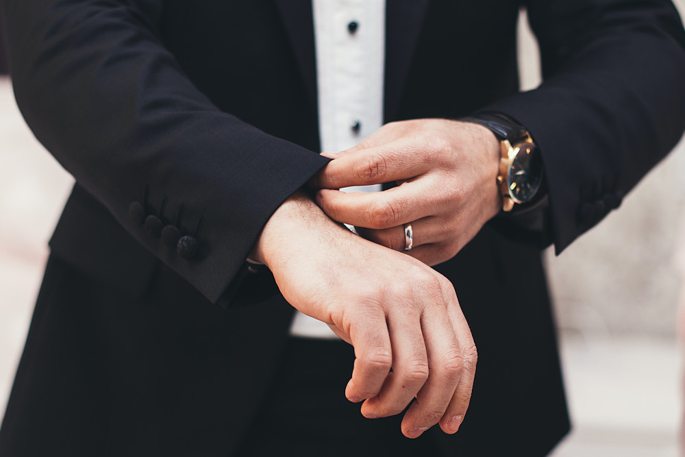 Photo of a man in a tuxedo checking his cuffs by Alvin Mahmudov on Unsplash